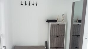 Una habitación con un banco, un armario, un espejo y una puerta.
