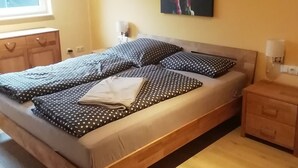 Un dormitorio con cama, mesitas de noche, una ventana y un cuadro en la pared.