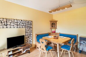 A cozy living room with a television, wooden furniture, a dining table, and a fireplace.