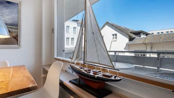 Ein Modellsegelboot auf einer Fensterbank, ein weißer Stuhl und ein Tisch mit einer Lampe.