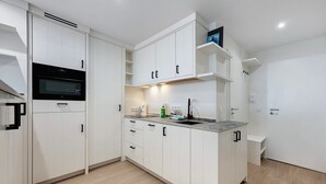 A modern kitchen with white cabinetry, a built-in oven, and a marble countertop.