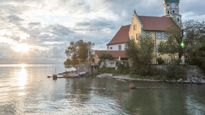 A historic building with a tower and a red roof by a calm body of water. - Holiday Apartment "Bodenseeblick" with Wi-Fi on Request (Meersburg)