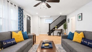 A living room with two grey sofas, a wooden coffee table, and a staircase leading to an upper floor. - The Heron House, King Bed Suite, *Spacious Remodeled House* (Joliet)