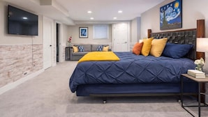 A bedroom with a bed, a TV, a painting, and a window. - The Heron House, King Bed Suite, *Spacious Remodeled House* (Joliet)