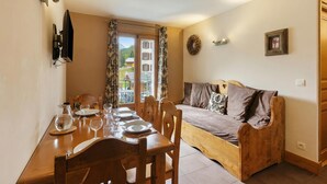 A dining area with a wooden table, chairs, and a sofa. - V Balme 14: Beside Ski Lift; Pool, Sauna & Gym, Vallorcine (Argentiere), France (Vallorcine (Argentiere))