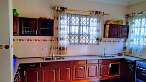 A kitchen with wooden cabinets, a double sink, and a window with decorative curtains.