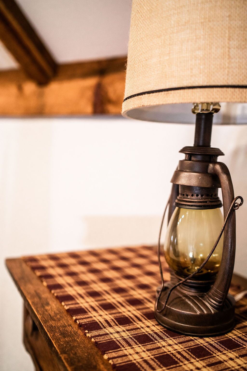 Eine Tischlampe im Vintage-Stil mit Stoffschirm auf einem Holztisch mit karierter Tischdecke.