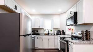 A modern kitchen with white cabinets, a stainless steel refrigerator, a built-in oven, and a microwave. - Family/Pet-Friendly Riverside Home w/Amazing Views (Prospect)