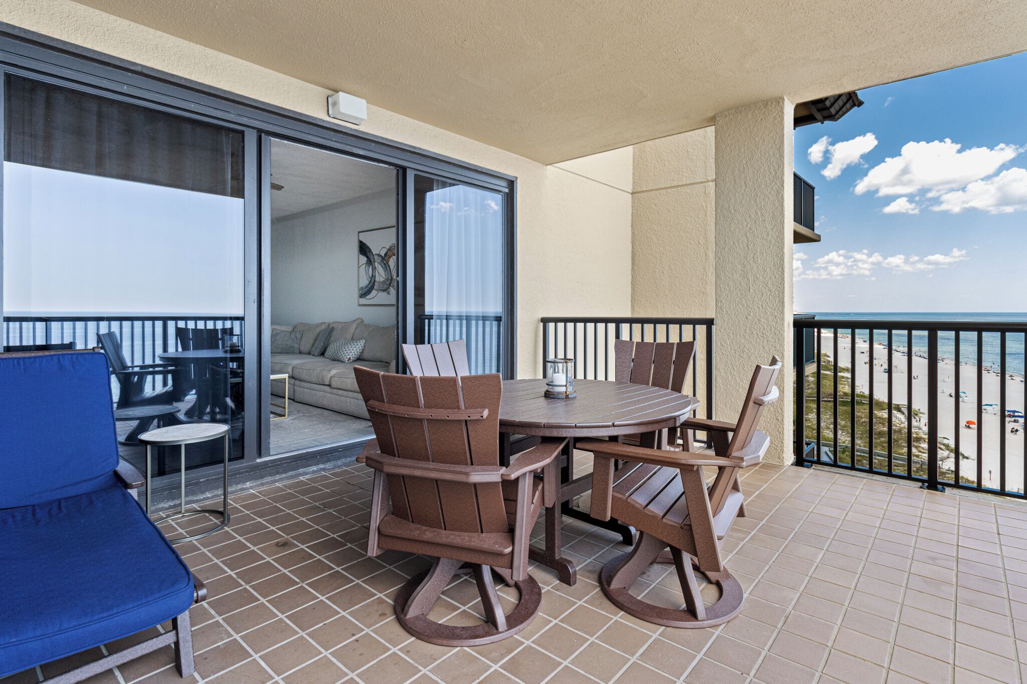 Un balcon avec un ensemble de mobilier de jardin, une chaise bleue et une vue sur la plage.