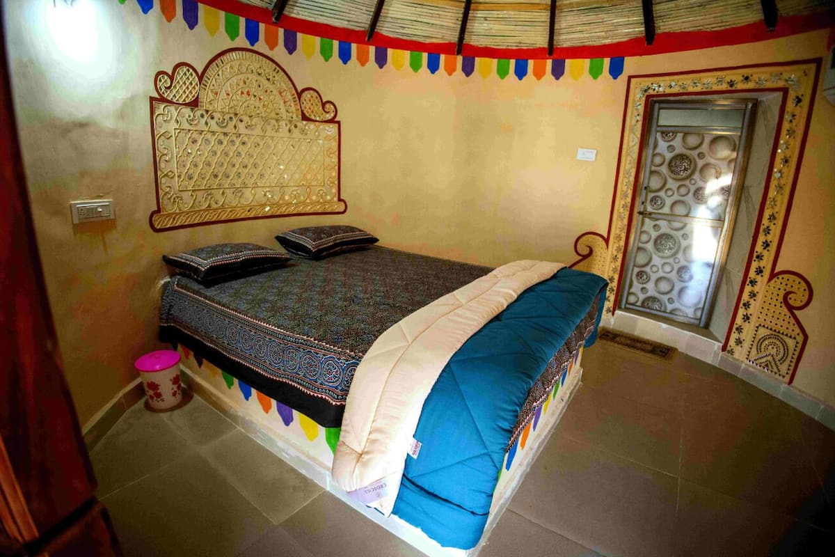 A bedroom with a bed, a decorative wall hanging, and a patterned door.
