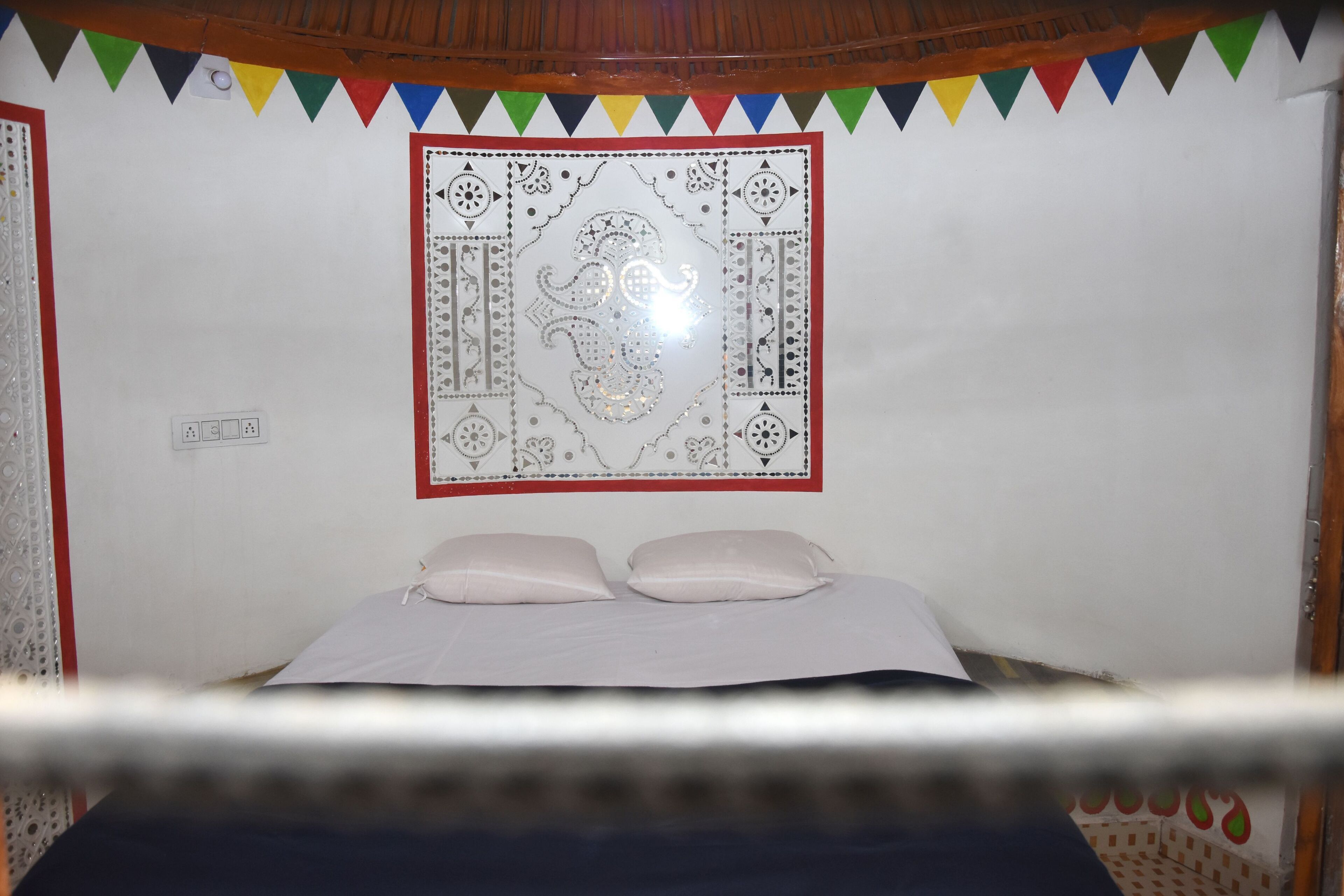 Une chambre avec un lit, des oreillers, une tapisserie murale et une prise de courant.