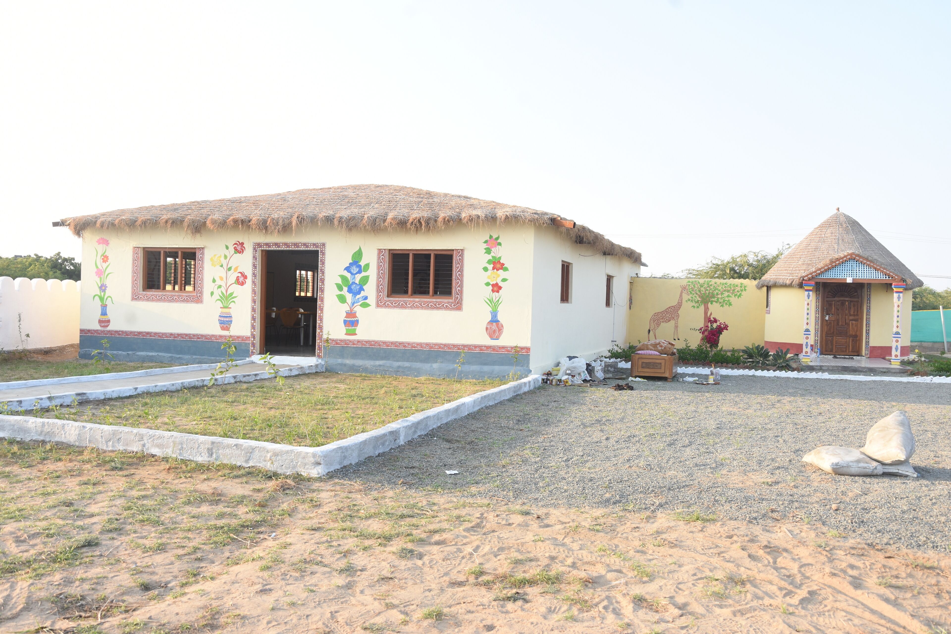 A house with a thatched roof, a small porch, and colorful floral decorations on the walls.