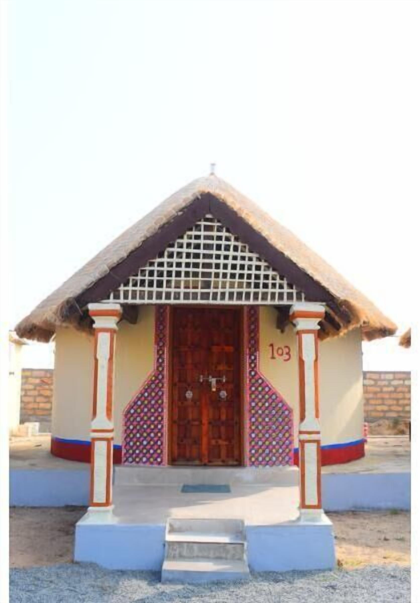 A small building with a thatched roof, a wooden door, and a number '103' on the wall.
