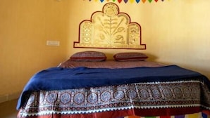 A room with a bed, a decorative headboard, and colorful hanging decorations. - Ram Rann Resort (Bhachau)
