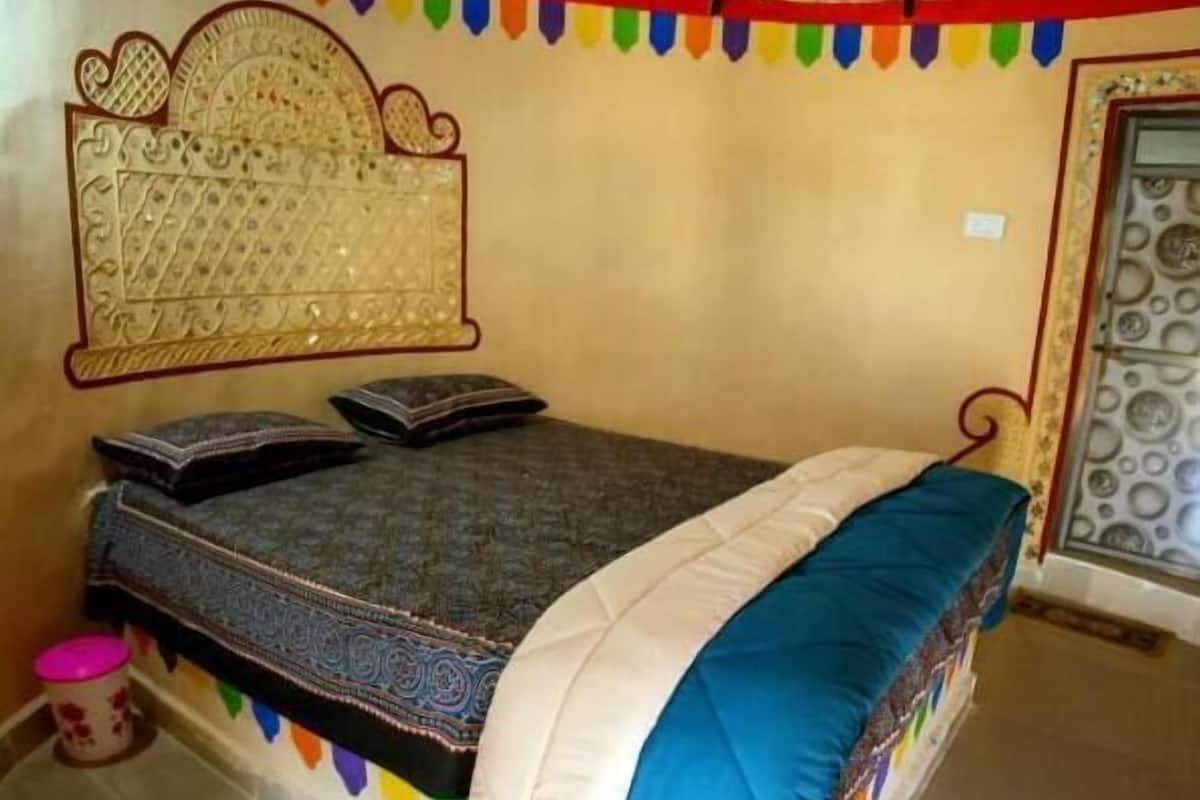 A bed with a patterned mattress, pillows, and a blue blanket.