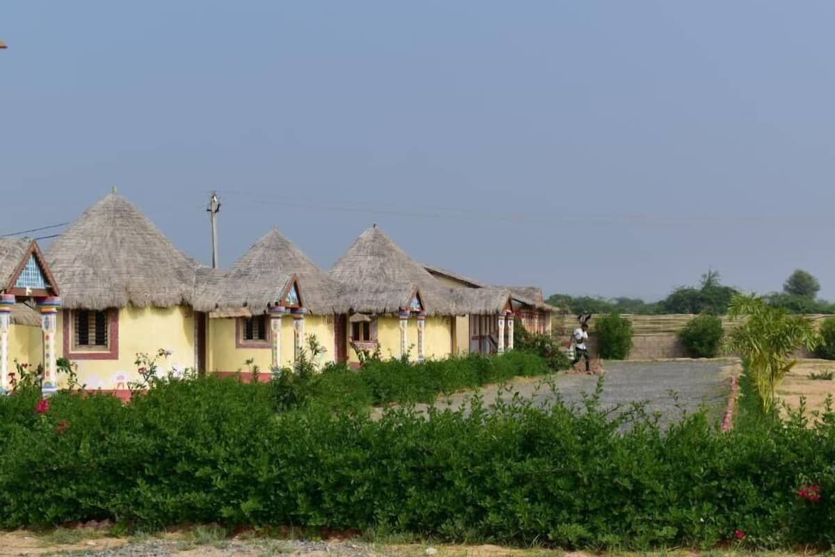 A row of thatched-roof houses with a person walking in the background.