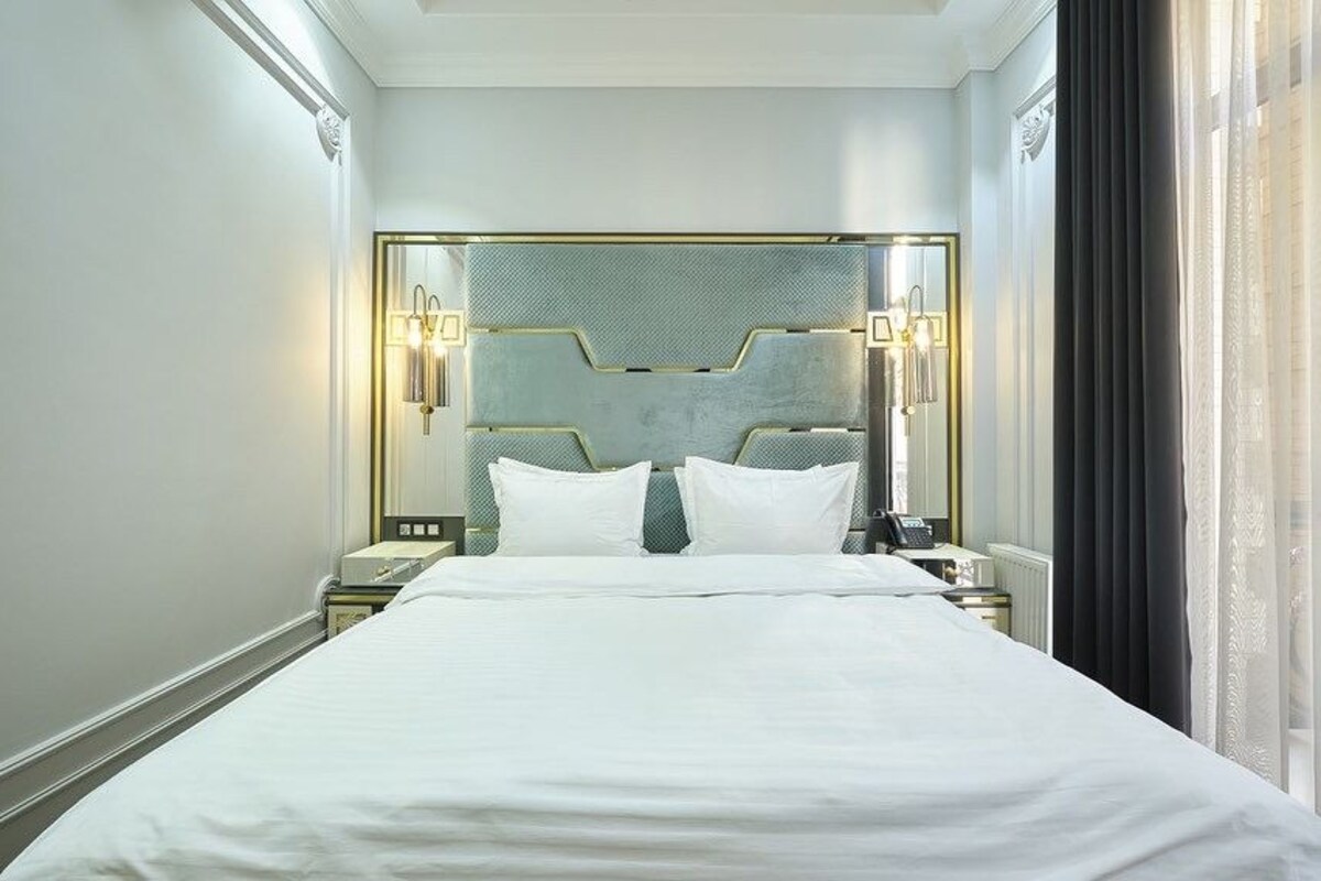 A hotel room with a large bed, a modern headboard, bedside lamps, and a nightstand.