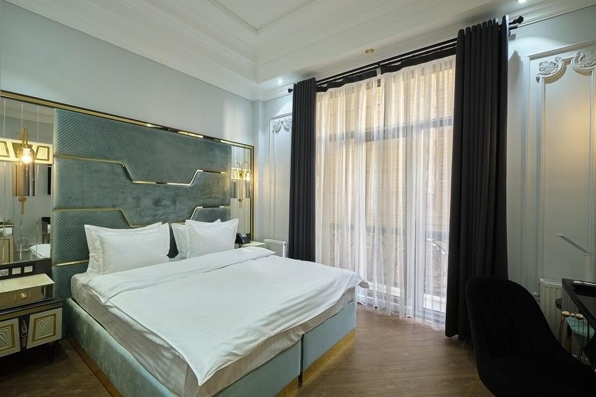Une chambre d’hôtel moderne avec un grand lit, une table de chevet, un bureau et une chaise.