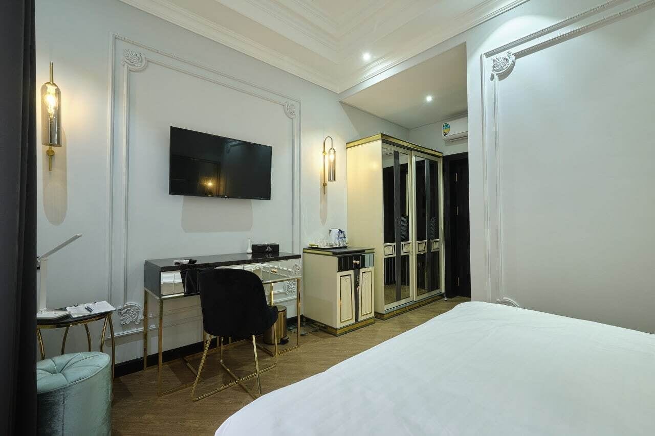 Habitación de hotel con cama, escritorio con silla, televisor, armario y baño.