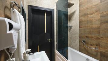 A modern bathroom with a dark wooden door, a glass shower enclosure, and a white sink.