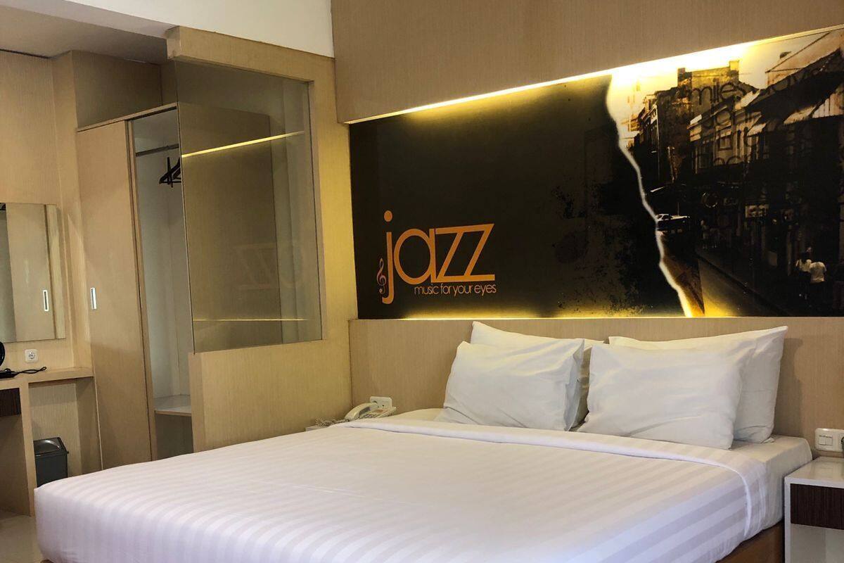 Een hotelkamer met een groot bed, een houten hoofdeinde en een poster aan de muur.