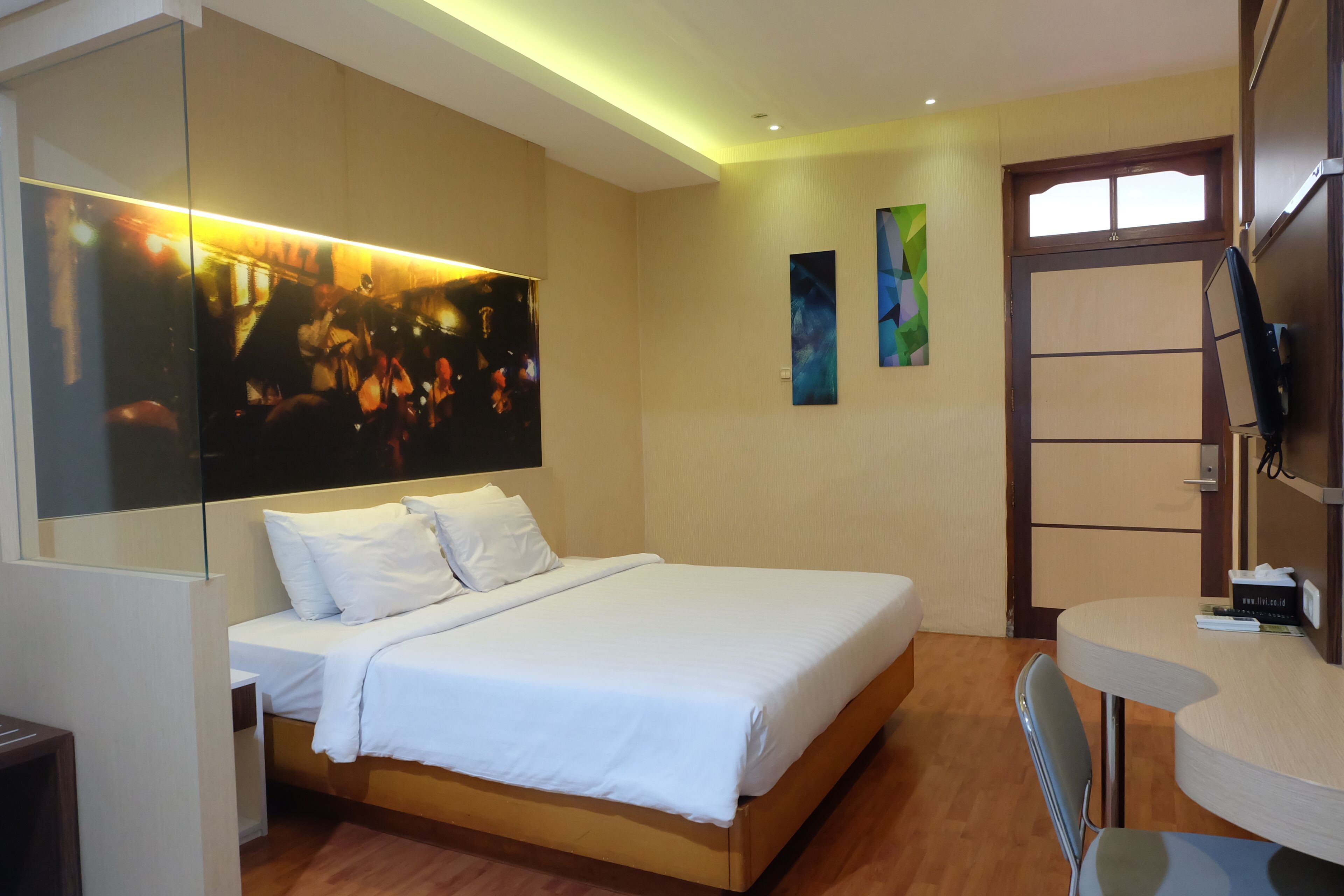 A modern hotel room with a large bed, a desk, and a television.