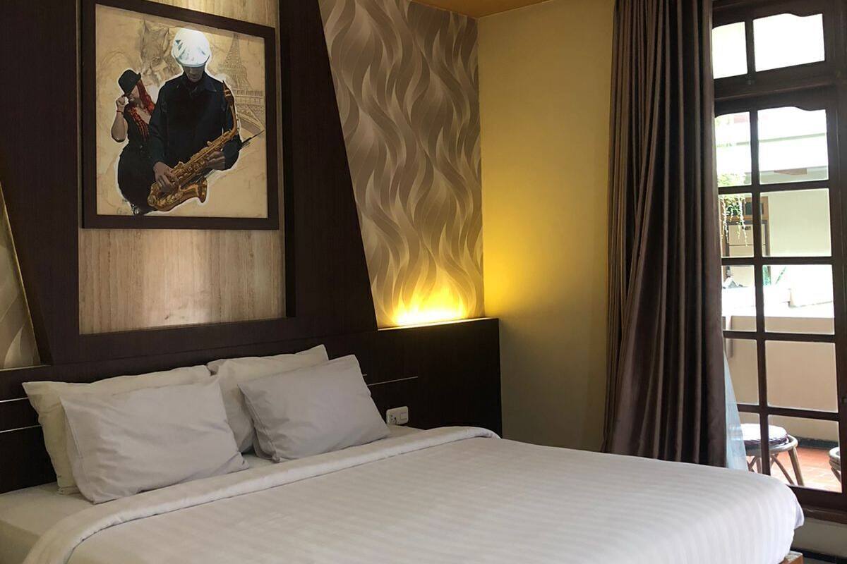 Een moderne hotelkamer met een groot bed, een kunstwerk aan de muur, een nachtkastje en een raam met gordijnen.