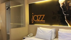 Een hotelkamer met een bed, een telefoon naast het bed, en een bord aan de muur met de tekst 'jazz muziek voor je ogen'.