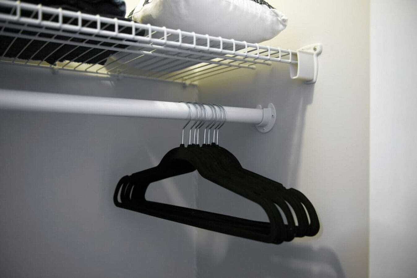 Een witte muur met een witte radiator en een zwarte hanger aan een witte metalen rek.