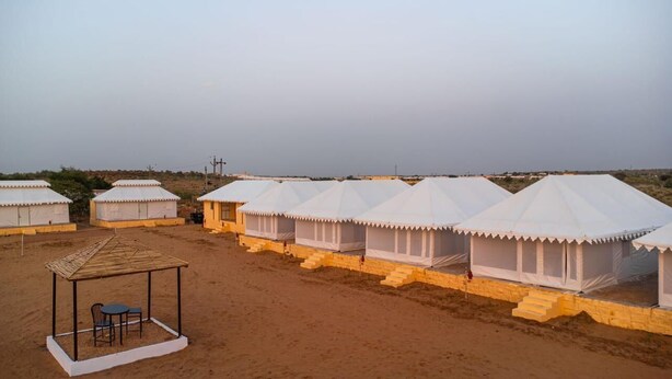 A row of white tents with a covered seating area in the foreground. - Desert Safari Camping Jaisalmer  (Jaisalmer)