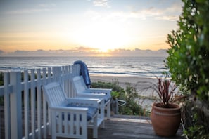 A deck with white chairs overlooking a beach at sunset. - TONIC on Boomerang Beach.. absolute beachfront & nestled in the dunes (Boomerang Beach)