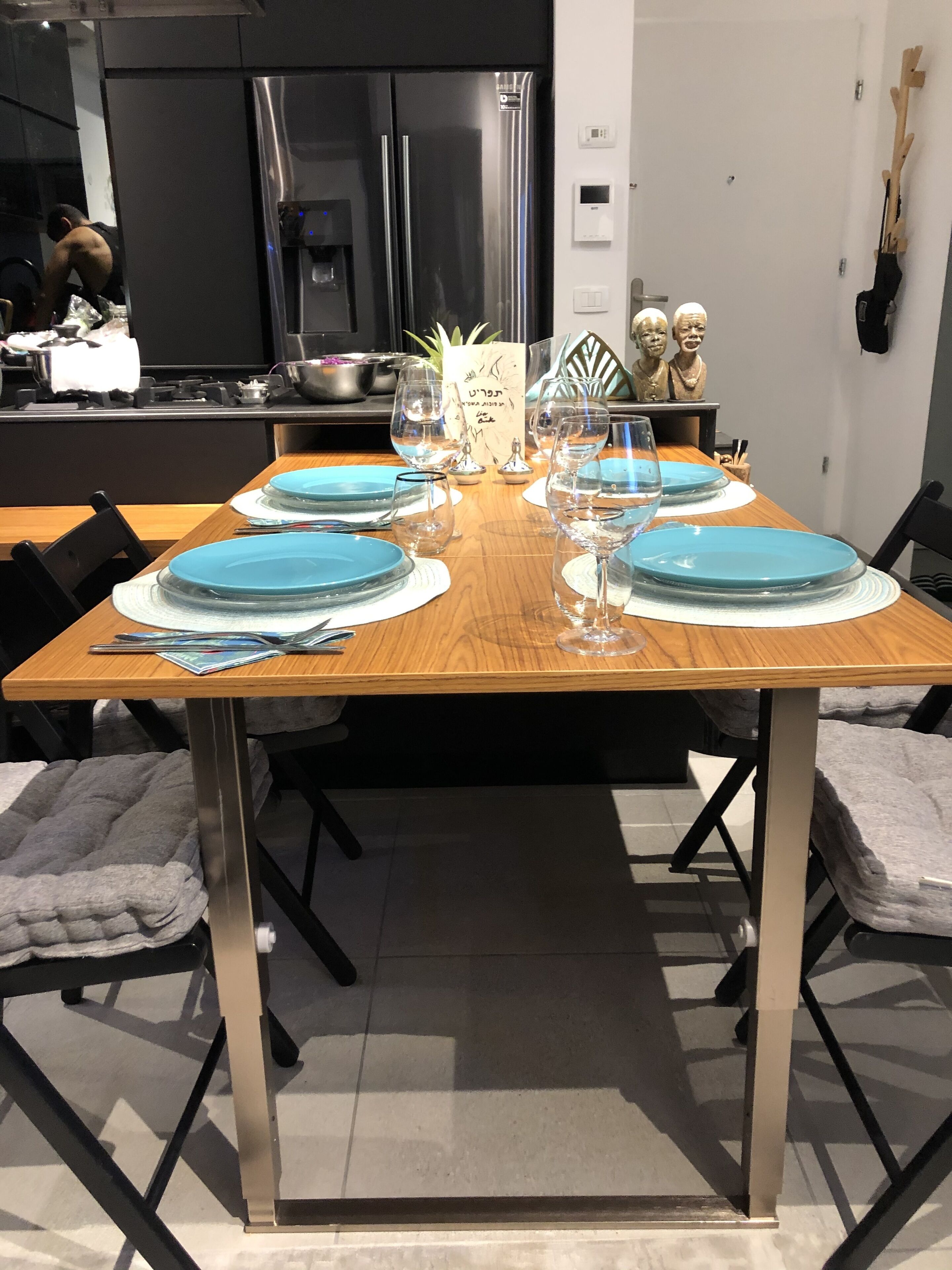 Een eettafel gedekt met blauwe borden, wijnglazen en een menukaart.