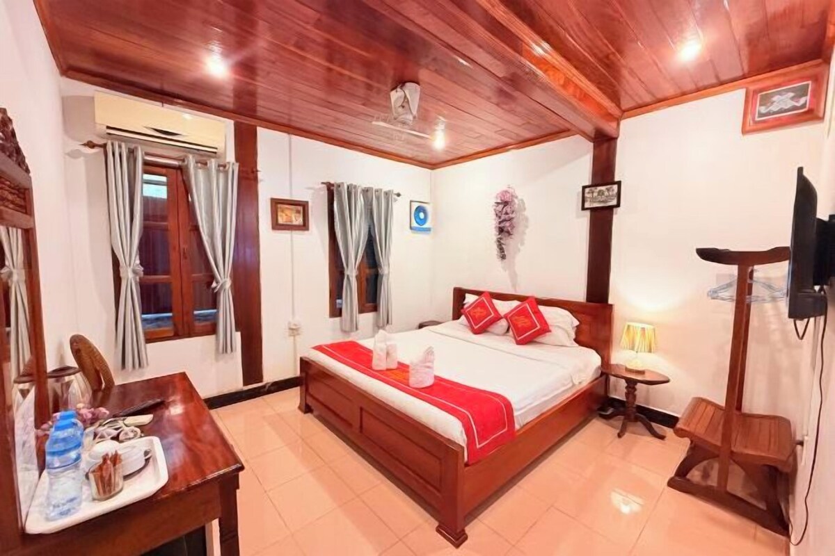 A wooden-paneled room with a bed, a small table, a chair, and a TV.