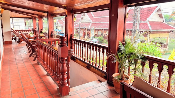 Un balcon fermé, doté de balustrades en bois, d’un sol carrelé et de plantes en pot.