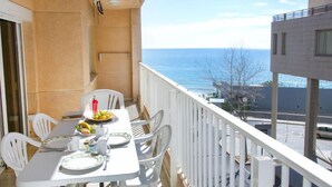 Un balcon avec une table dressée pour deux personnes, donnant sur la mer.