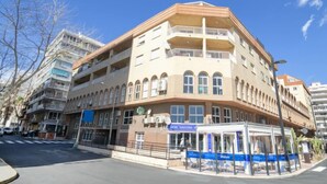 Un immeuble à plusieurs étages, avec une entrée d’angle, des balcons et un café situé au rez-de-chaussée.