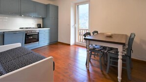 A modern kitchen with blue cabinets, a dining table with chairs, and a chandelier. - Matilda by Interhome (Barcis Lake)