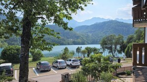 A view of a parking area with cars, a lake, and mountains in the background. - Matilda by Interhome (Barcis Lake)