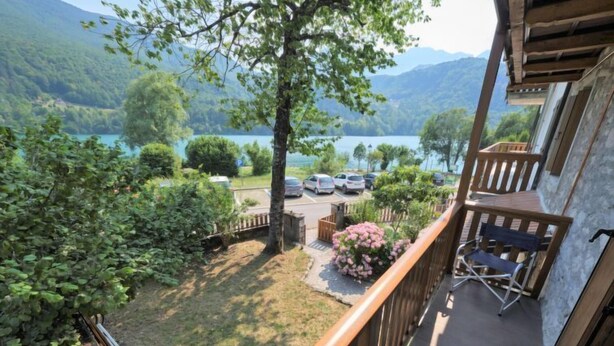 A balcony with a view of a lake and mountains, wooden deck, and outdoor seating. - Matilda by Interhome (Barcis Lake)