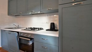 A modern kitchen with grey cabinets, a white countertop, stainless steel appliances, and a coffee maker. - Matilda by Interhome (Barcis Lake)