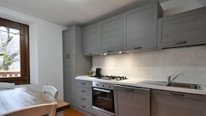 A compact kitchen with grey cabinets, a white countertop, a stove, and a sink. - Apartment Elsa by Interhome (Barcis Lake)
