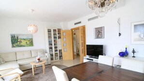 Una sala de estar moderna con un sofá, sillas, una mesa de centro, un televisor y una estantería.