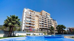 Un hotel de varios pisos con una piscina en primer plano.