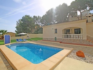 A rectangular pool with a tiled edge, surrounded by a stone deck. There are two lounge chairs and a small umbrella. - Villa Sandra by Interhome (Calpe/Calp)