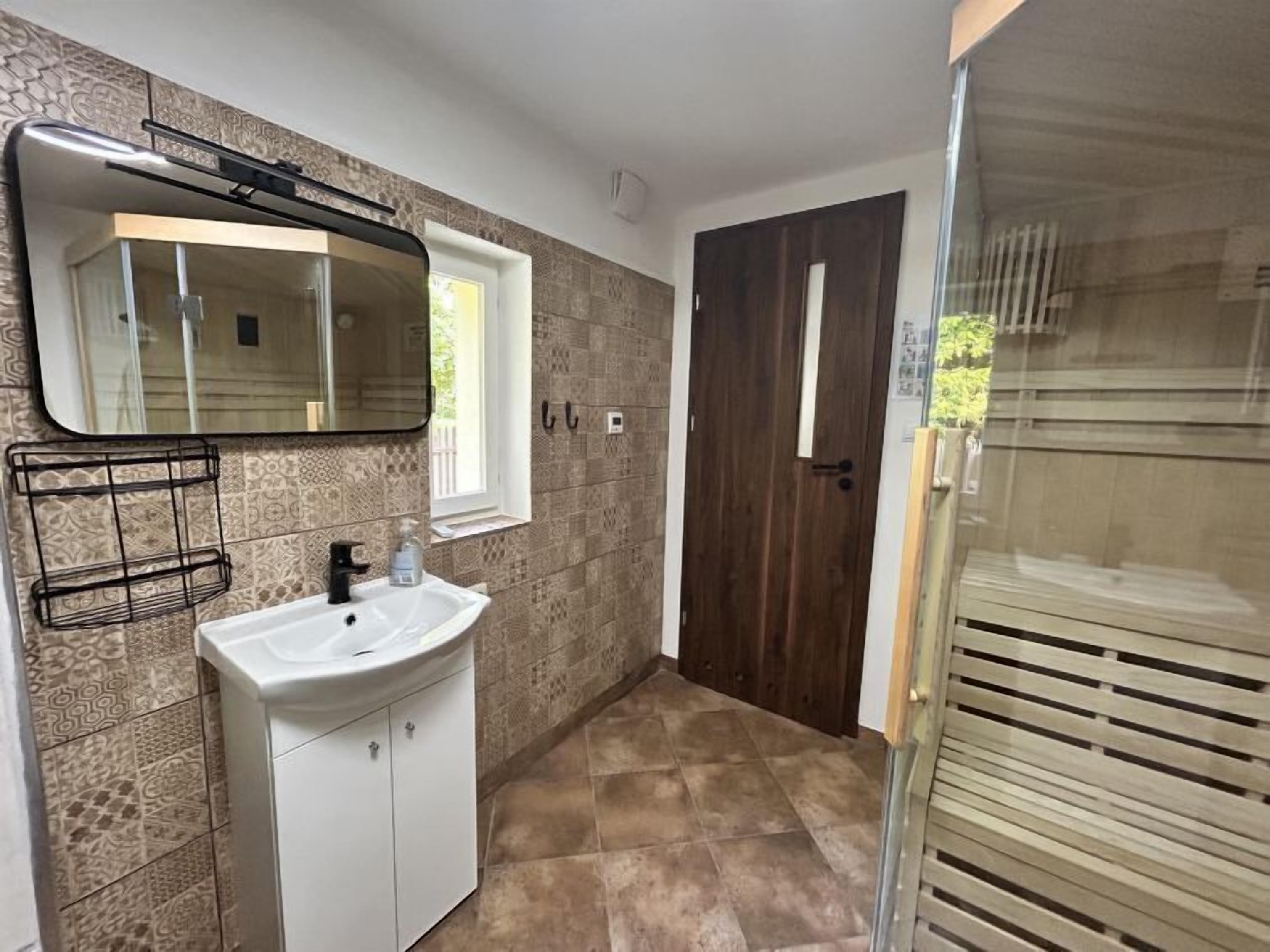 A bathroom with a white sink, a mirror, and patterned tiles.