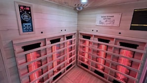 A sauna room with wooden walls, a control panel, and multiple benches. - Apartment Frushi by Interhome (Grossschönau)
