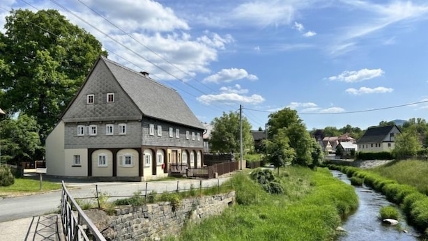 A traditional house with a stone facade and a sloped roof, located beside a narrow water channel. - Apartment Frushi by Interhome (Grossschönau)
