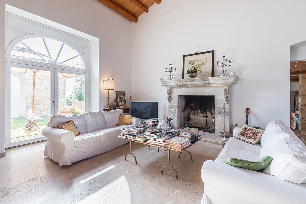 A living room with a fireplace, white sofas, and a coffee table with books.