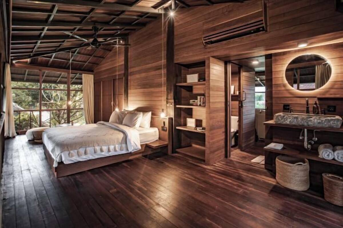 A spacious bedroom with a large bed, wooden walls, and a built-in wardrobe.