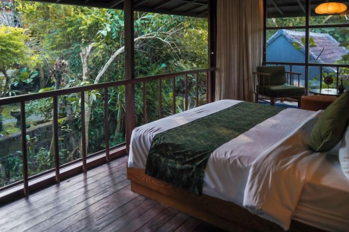 A bedroom with a large window, a bed, and a chair.